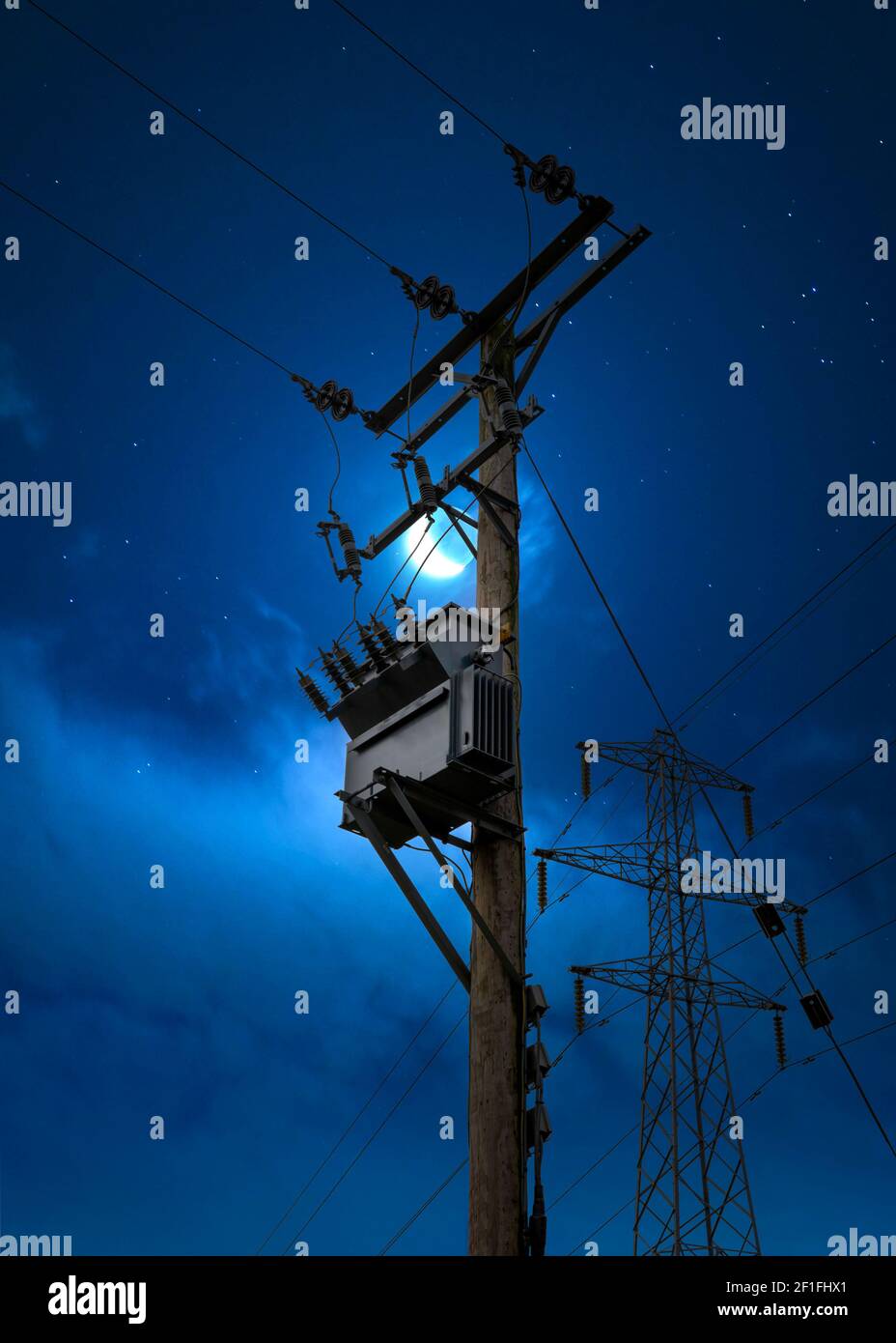 Elektrische Power Pylon Kabel bei Nacht blau Stunde Mond Himmel. Hochspannungs-Umspannwerk auf Holzmast Tower Silhouette gegen launisch hell sogar Stockfoto