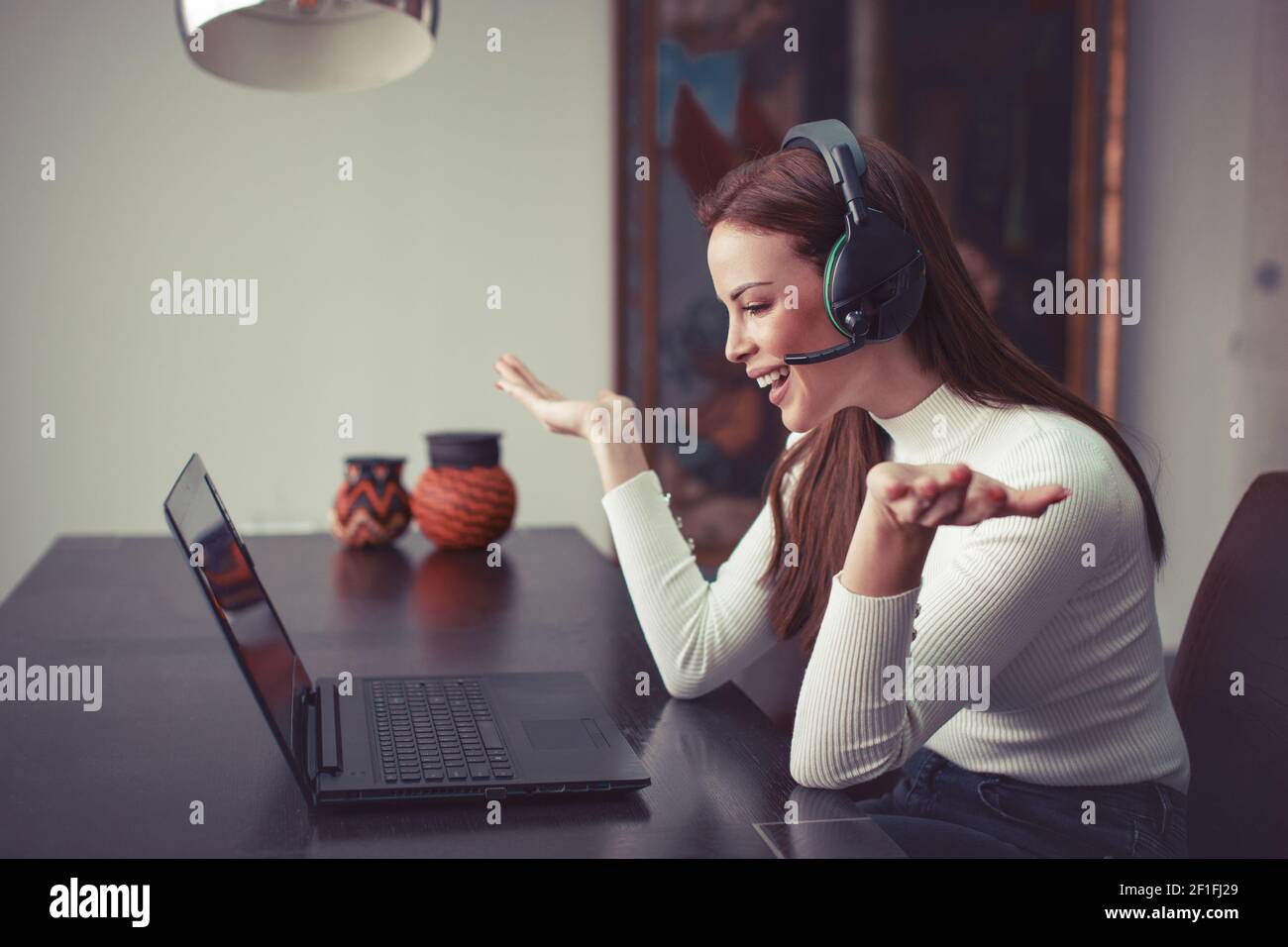Glückliche junge kaukasische Frau mit Headset hilft online von Laptop, Kunden-Support Stockfoto