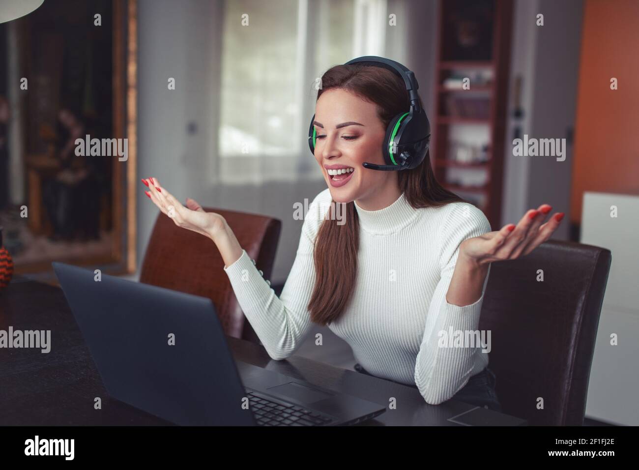 Glückliche junge Frau mit Headset erklären Problem im Home Office, Online-Kommunikation Stockfoto