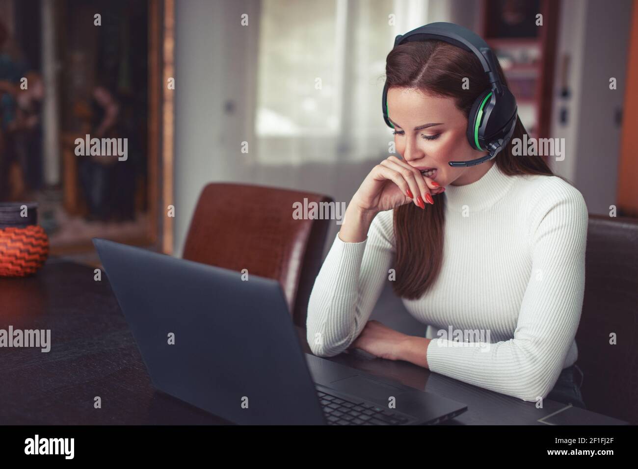 Junge kaukasische Frau mit Headset verdorben etwas online Stockfoto