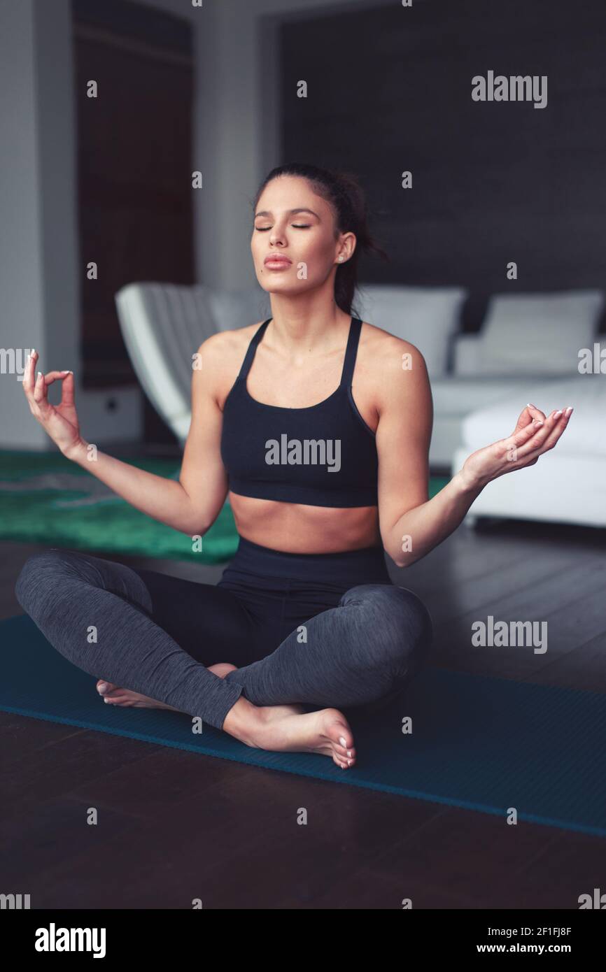 Junge kaukasische Frau meditiert während Yoga-Übungen drinnen, Augen geschlossen, geistige Gesundheit Stockfoto
