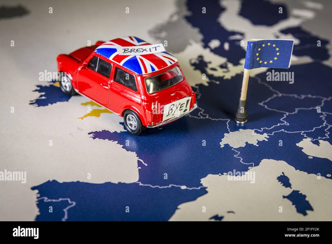 Rote Oldtimer mit Union Jack Flagge und brexit oder bye Worte über eine UE Karte und Flagge. Stockfoto