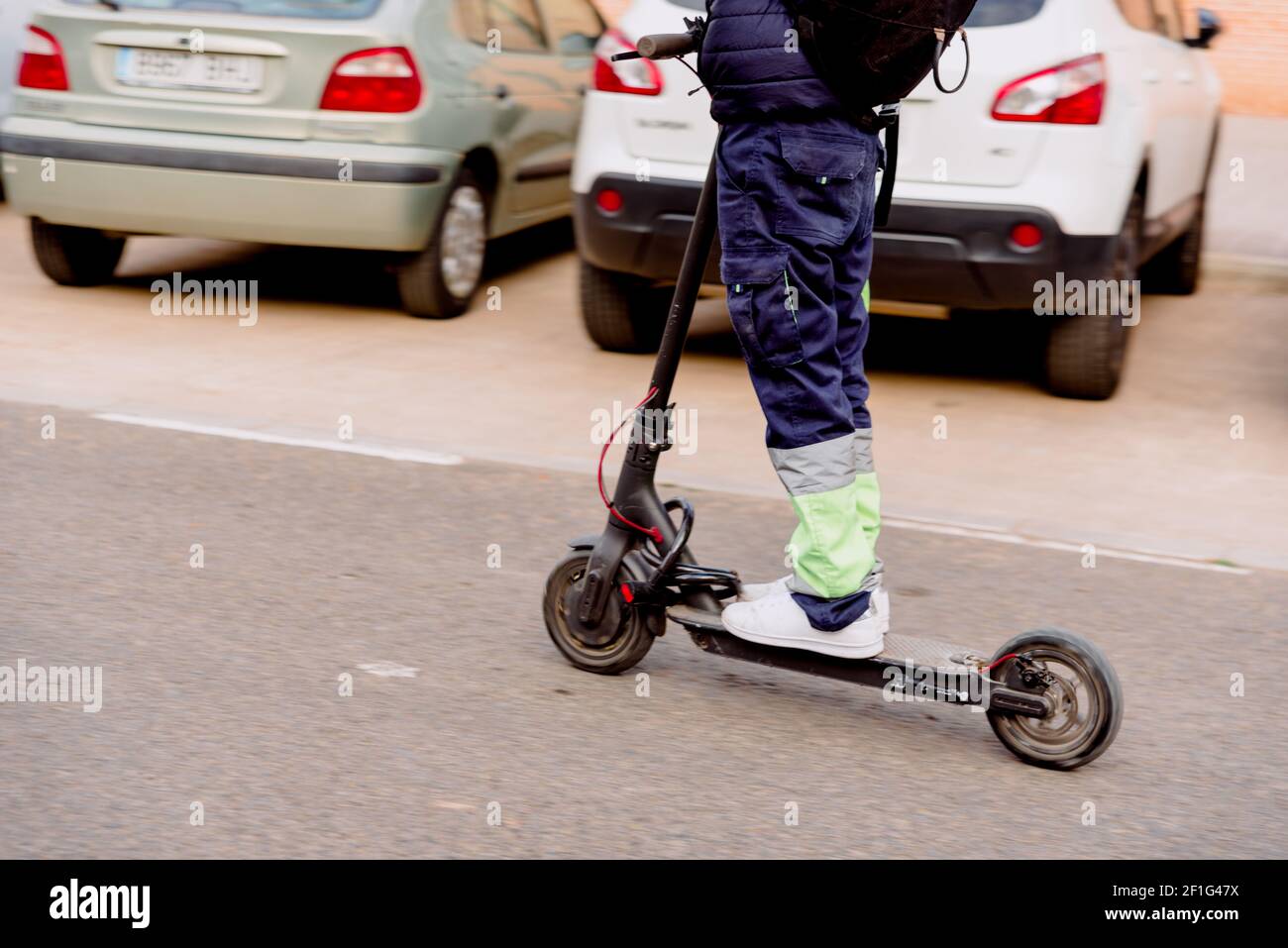 Valencia, Spanien - 7. März 2021: Ein prekärer Arbeiter fährt mit einem Elektroroller zu seinem Arbeitsplatz. Stockfoto