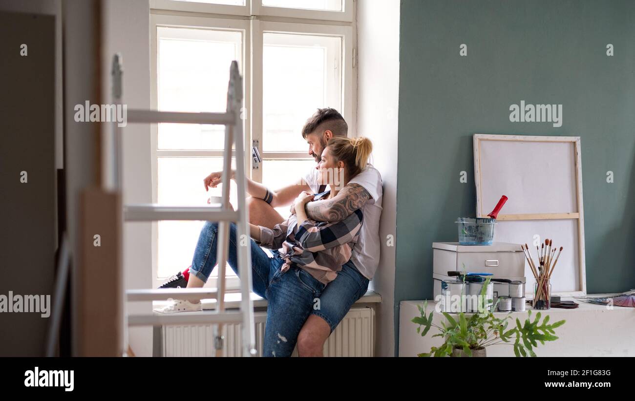 Mittlere Erwachsene Paar sitzt drinnen zu Hause, Umzug und diy-Konzept. Stockfoto
