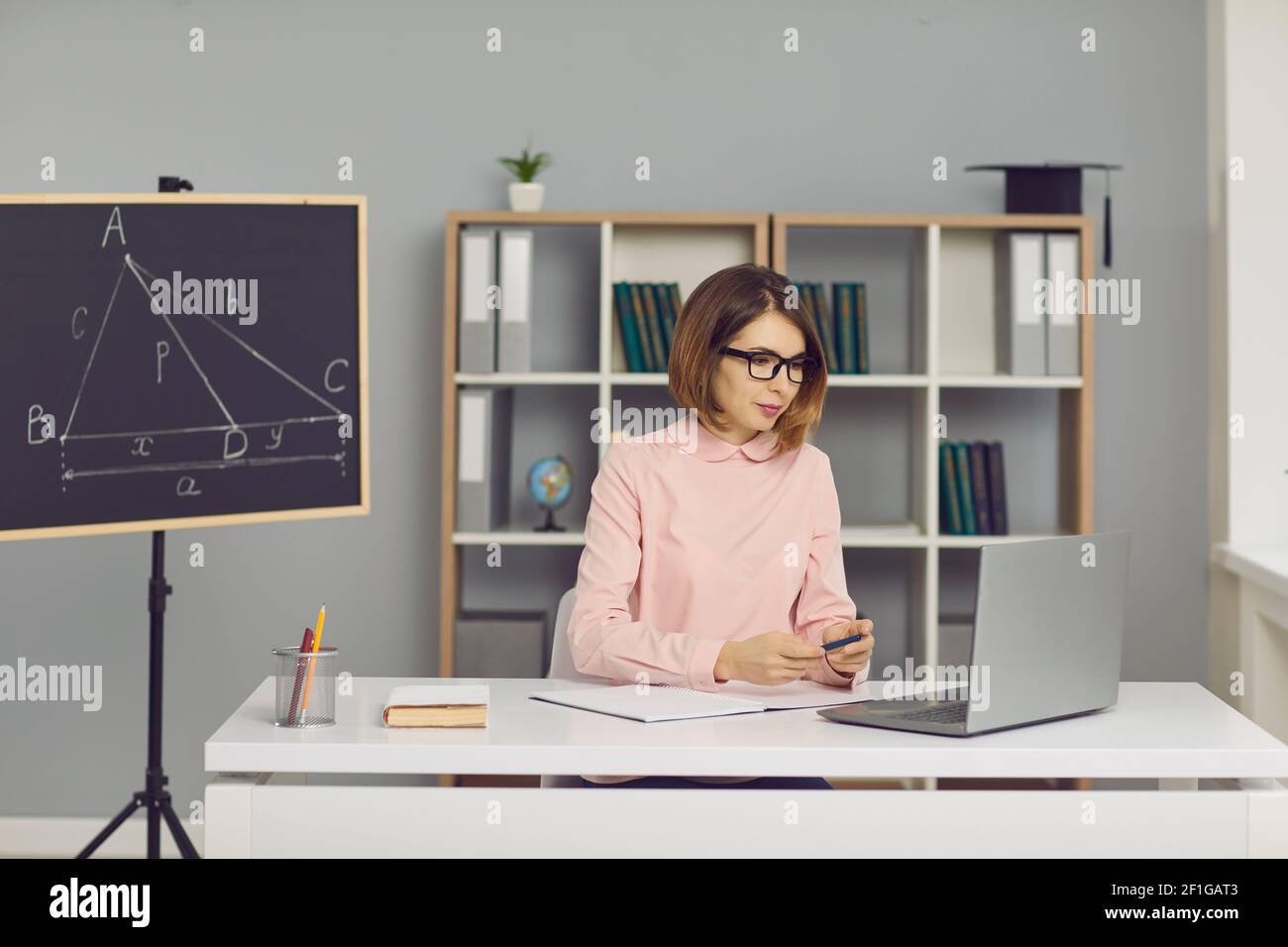 Der Lehrer mit Brille sitzt vor einem Laptop und führt per Video-Chat eine Online-Mathematikstunde durch. Stockfoto