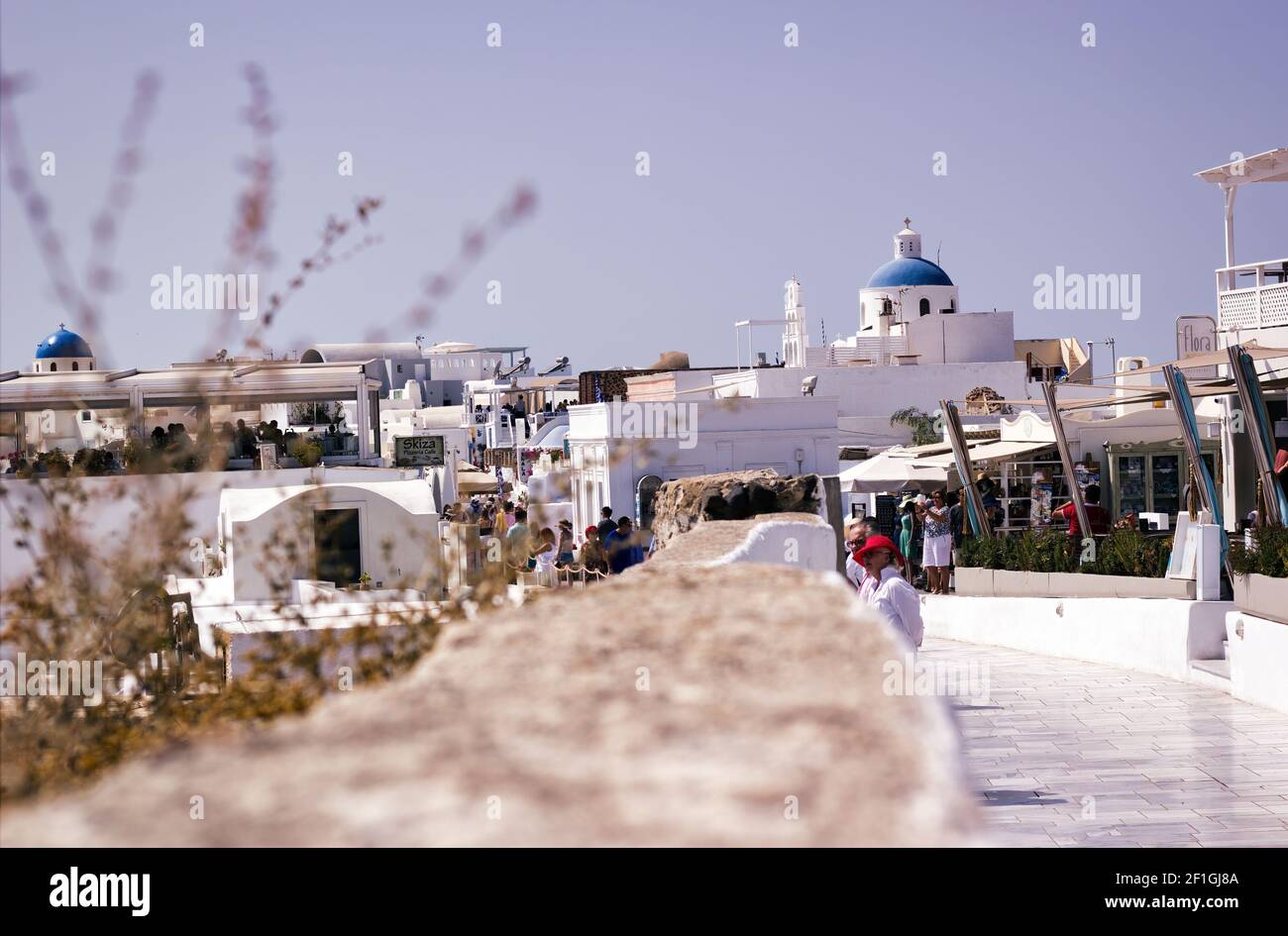 Santorini, Griechenland - 11. September 2017: Eine Handelsstraße mit Leuten, die in den Cafés gegen typische blaue Kuppelkirche spazieren und essen Stockfoto