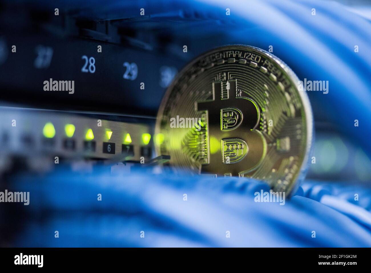 Goldene Bitcoin simbol in blauen Kabeln Nahaufnahme. Kryptowährung, digitales Curency-Konzept Nahaufnahme Stockfoto