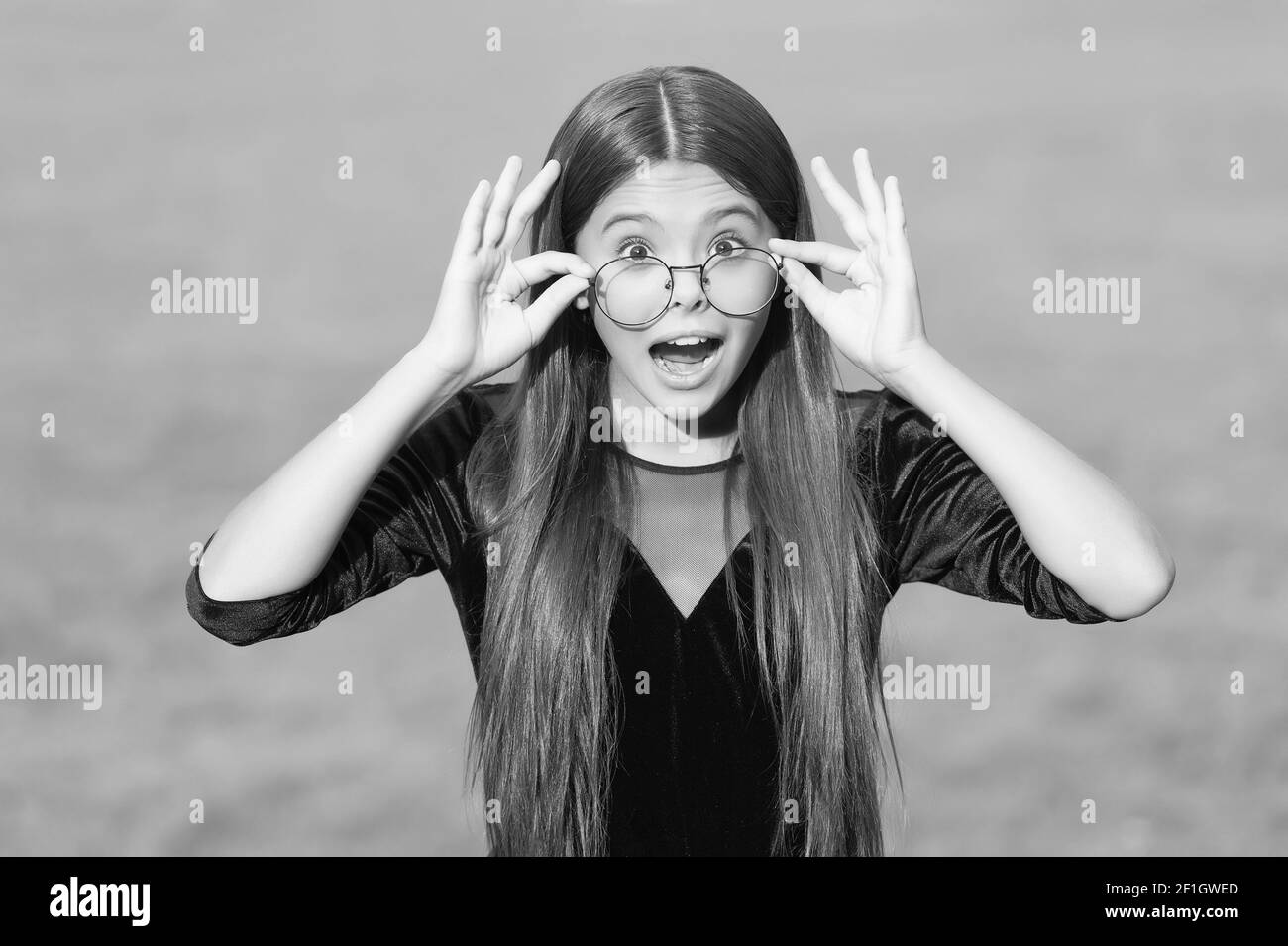 Adorable kleines Kind mit überrascht aussehen und offenen Mund halten Korrektiv Brille rutscht nach unten Nase grünes Gras sonnigen Sommer im Freien, Sehvermögen. Stockfoto