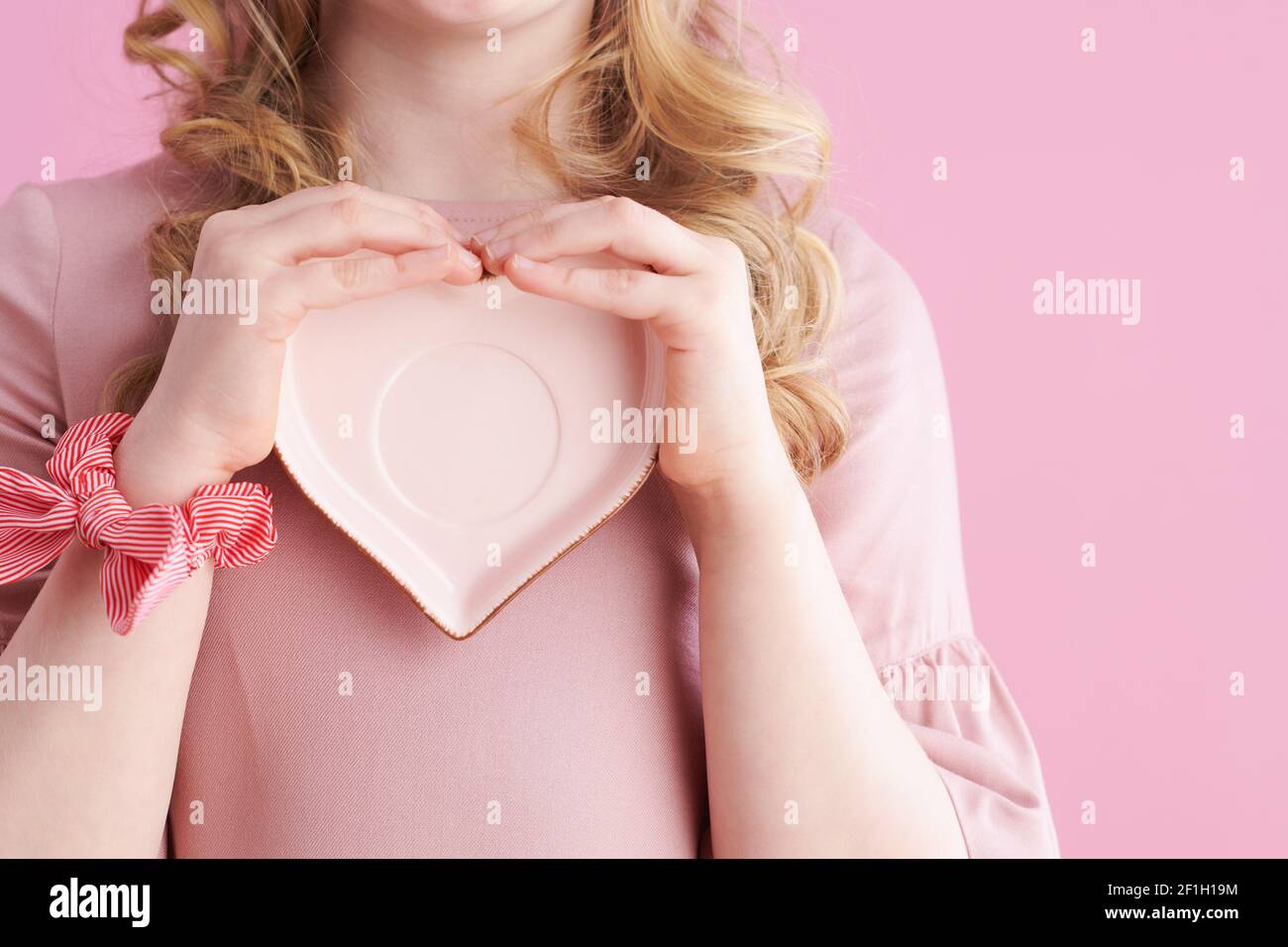 Nahaufnahme auf Mädchen mit herzförmigen Untertasse vor rosa Hintergrund. Stockfoto