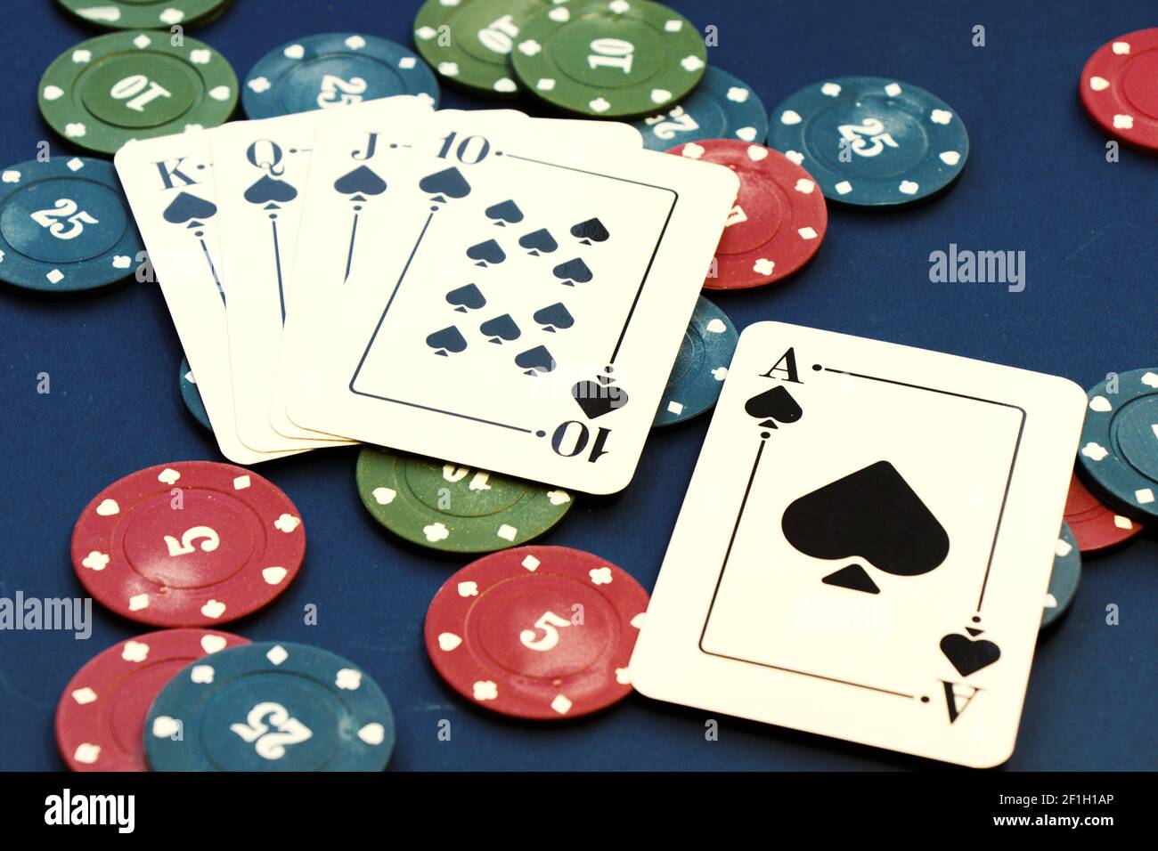 Eine Nahaufnahme von Royal Flush Karten von Kleeblätter und Chips verbreiten sich auf einem Pokertisch mit einem separaten Ass Stockfoto