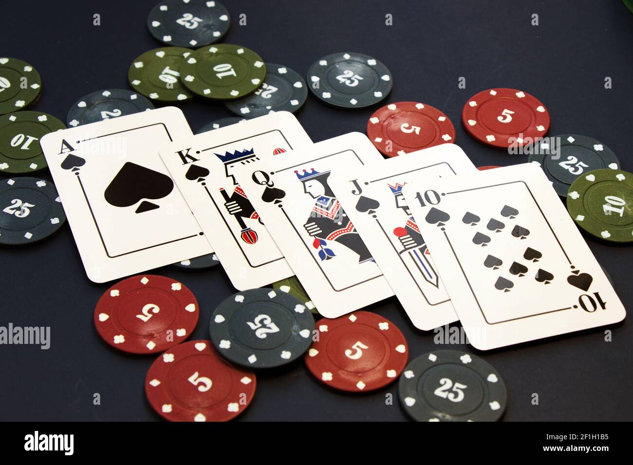 Eine Nahaufnahme von Royal Flush Karten von Kleeblätter und Chips verteilt auf einem Pokertisch Stockfoto