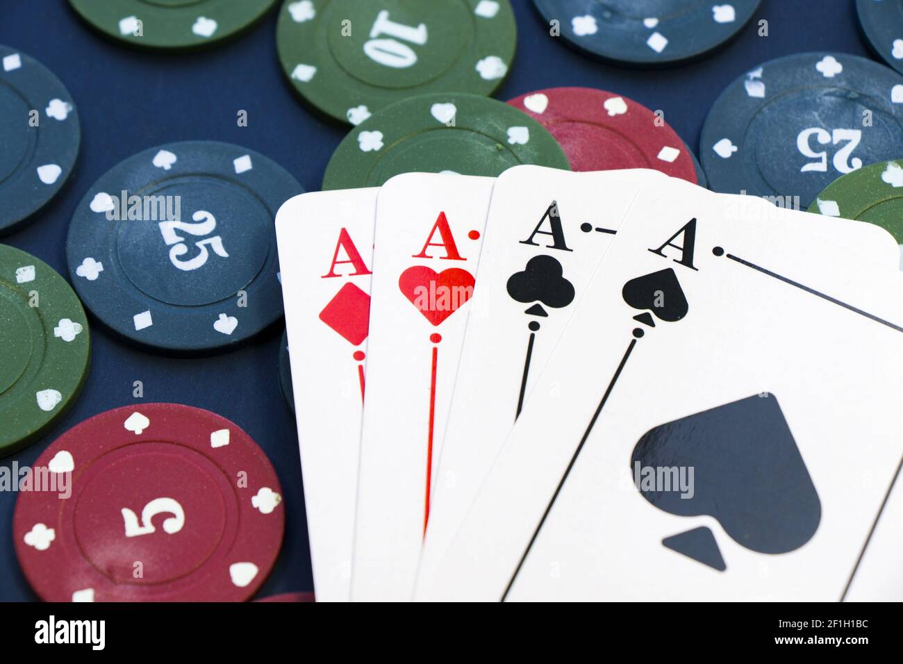Ein Nahaufnahme von vier Assen und verschiedenen Chips verteilt Auf einem Pokertisch Stockfoto