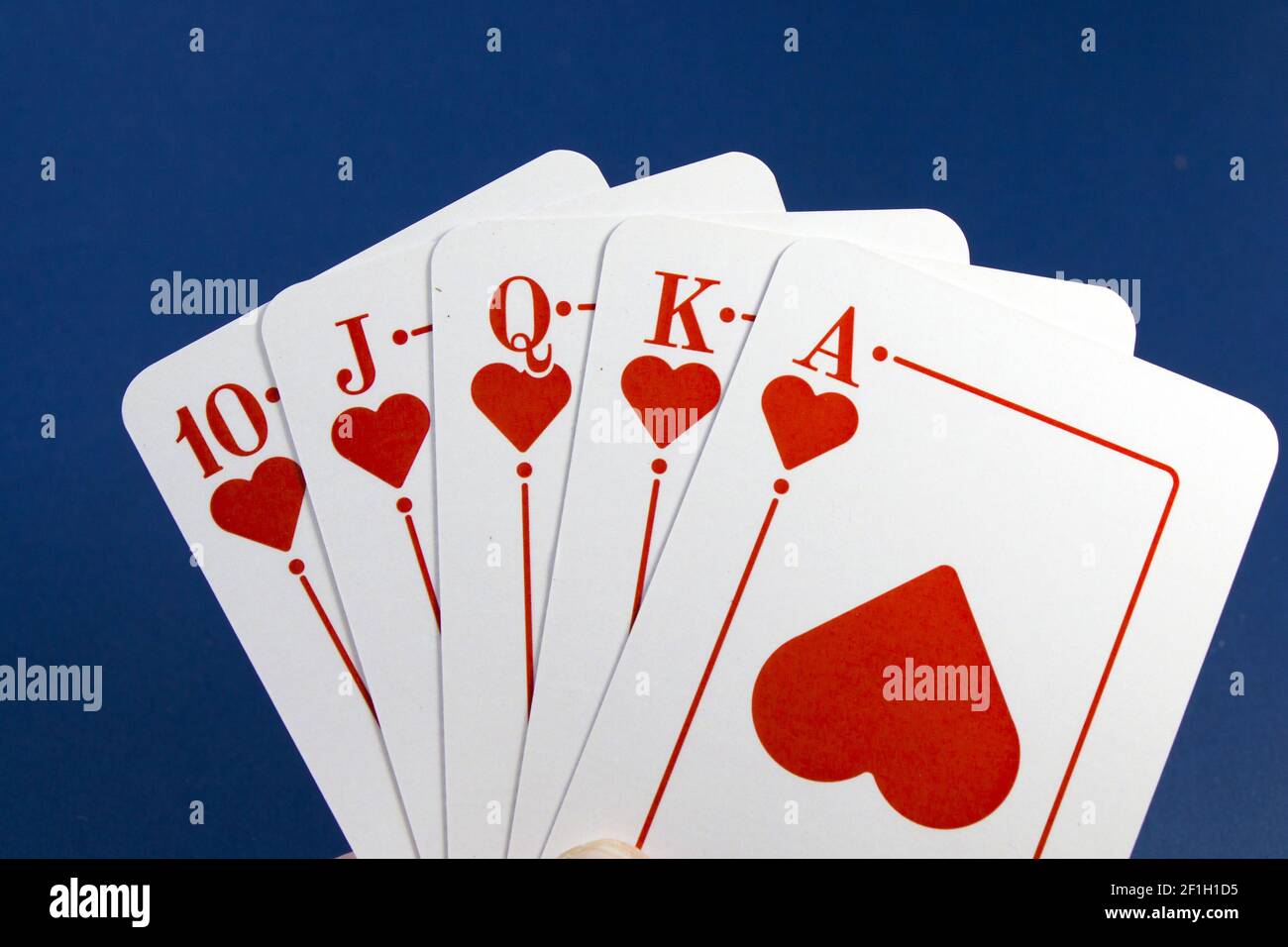Nahaufnahme der Hand eines Mannes, der das Herz Royal hält Flush Karten auf einem Pokertisch Hintergrund Stockfoto
