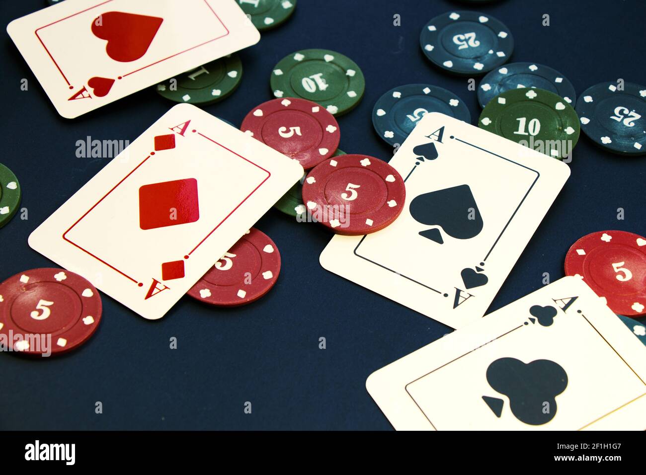 Ein Nahaufnahme von vier Assen und verschiedenen Chips verteilt Auf einem Pokertisch Stockfoto