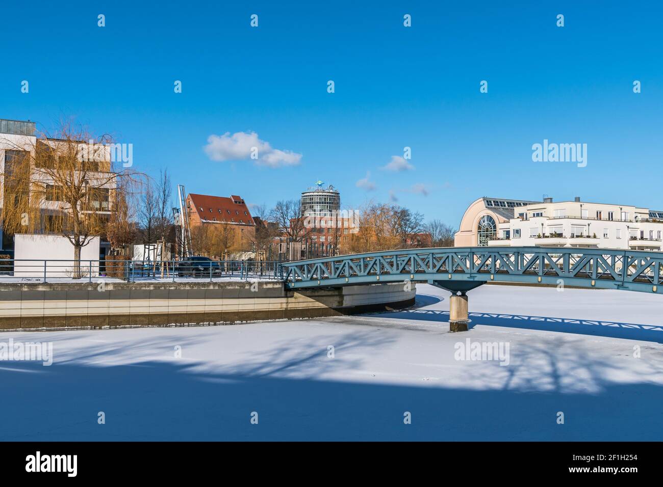 Berlin, Deutschland - 12. Februar 2021: Gefrorenes Hafenbecken Tegeler Hafen mit Fußgängerbrücke, alten und modernen Gebäuden, Humboldt-Bibliothek und der Klinik Stockfoto