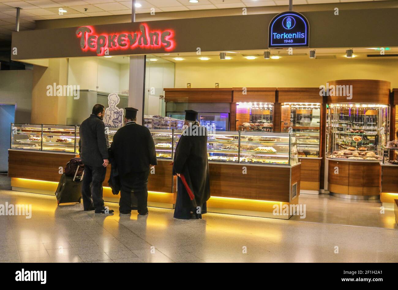 1-8-2018 Athen Griechenland - griechisch-orthodoxe Priester unterhalten sich mit einem Reisende in einer Bäckerei am Flughafen Stockfoto