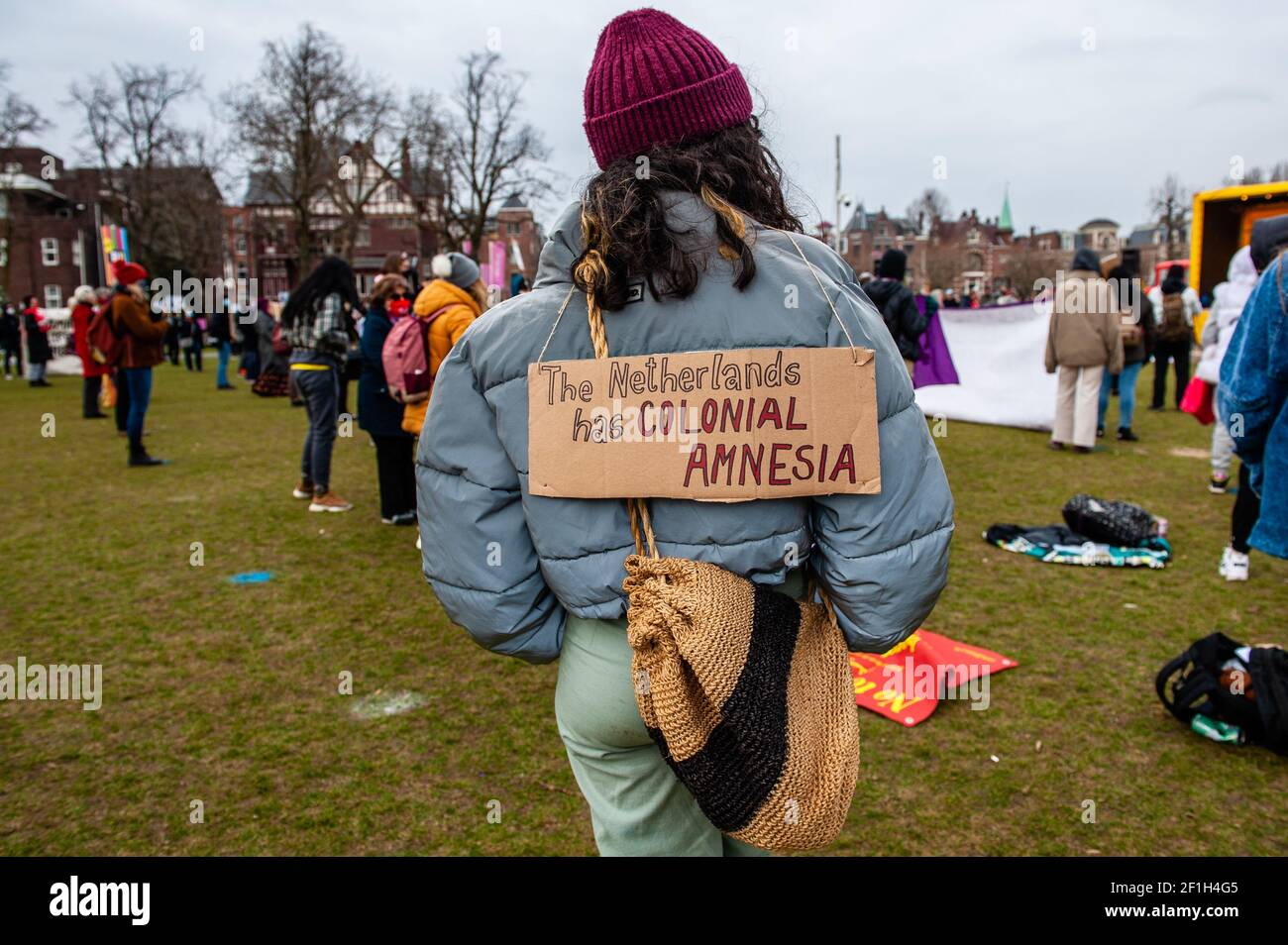 Während des marsches wird eine Frau mit einem Plakat auf dem Rücken gesehen.die Veranstaltung wurde von '8 maartcomité' organisiert, einer unabhängigen Initiativgruppe aktiver Frauen aus verschiedenen Organisationen und Hintergründen, die sich für die Organisation der militanten Feier des Internationalen Frauentags in Amsterdam engagieren. Auf dem Museumplein versammelten sich Hunderte von Menschen, um weltweit für gleiche Rechte für Frauen zu kämpfen. Stockfoto