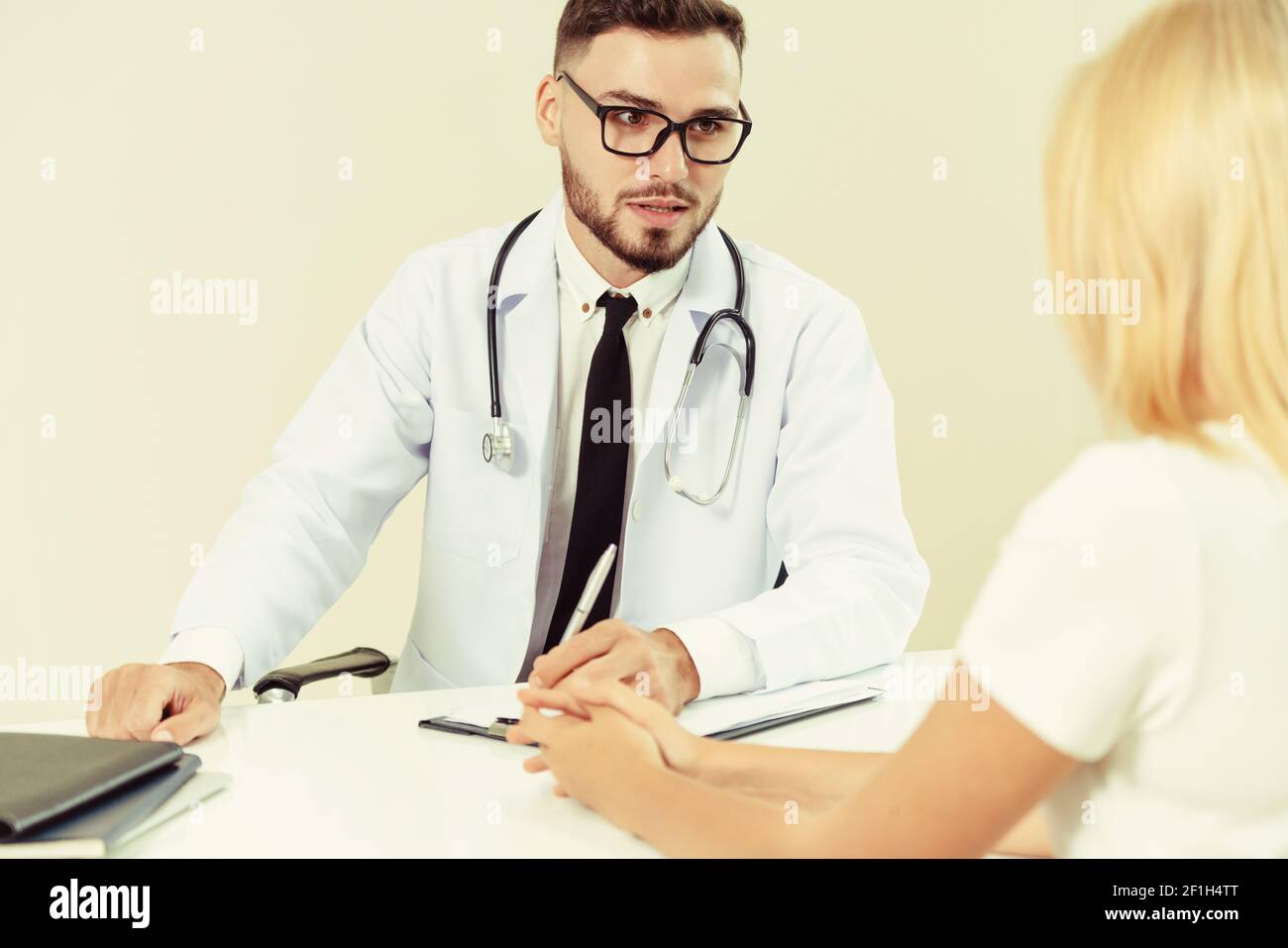 Männlicher Arzt spricht mit weiblichen Patienten im Krankenhaus. Gesundheitswesen und medizinische Betreuung. Stockfoto