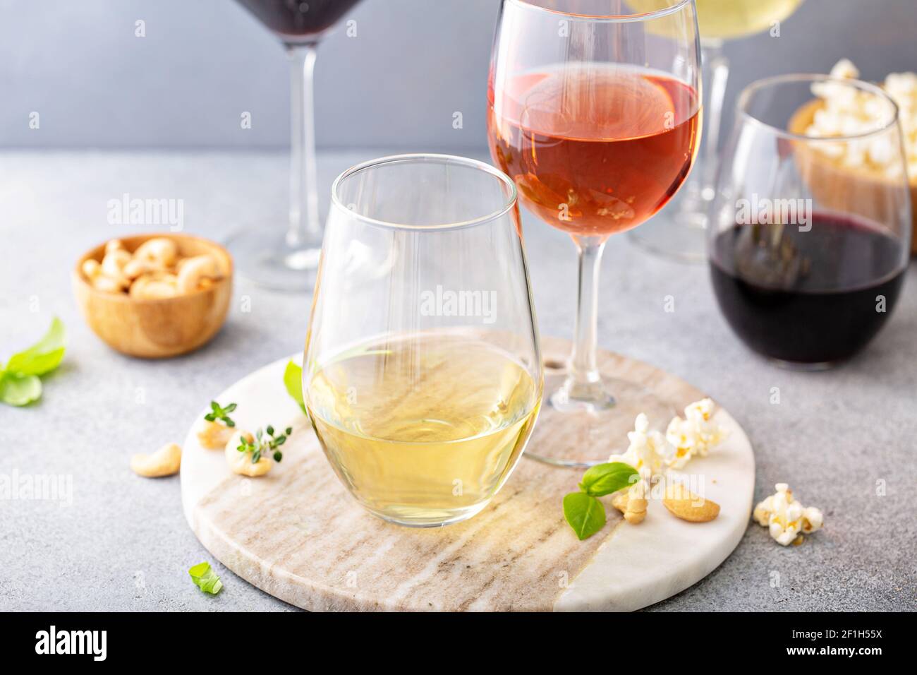 Rot, Weißwein und Rose in verschiedenen Gläsern Stockfoto
