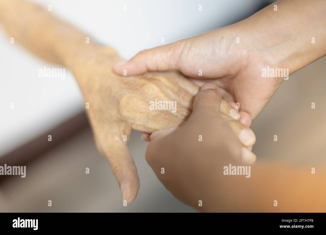 Weibliche Hand hält mit ihrem Vater für die Unterstützung älteren alten Mann in ihrem Haus, während ihr Vater ist geduldig und wartet auf ihre Gesundheit zu erholen. Stockfoto