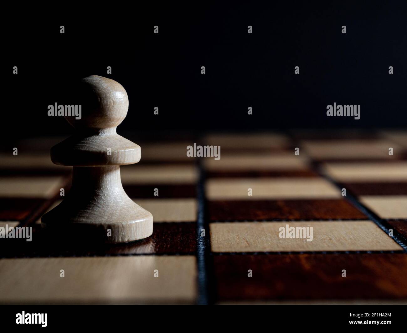 Ein Holzschach, das auf dem Schachbrett steht. Hoher Fotokontrast, Low-Key. Stockfoto