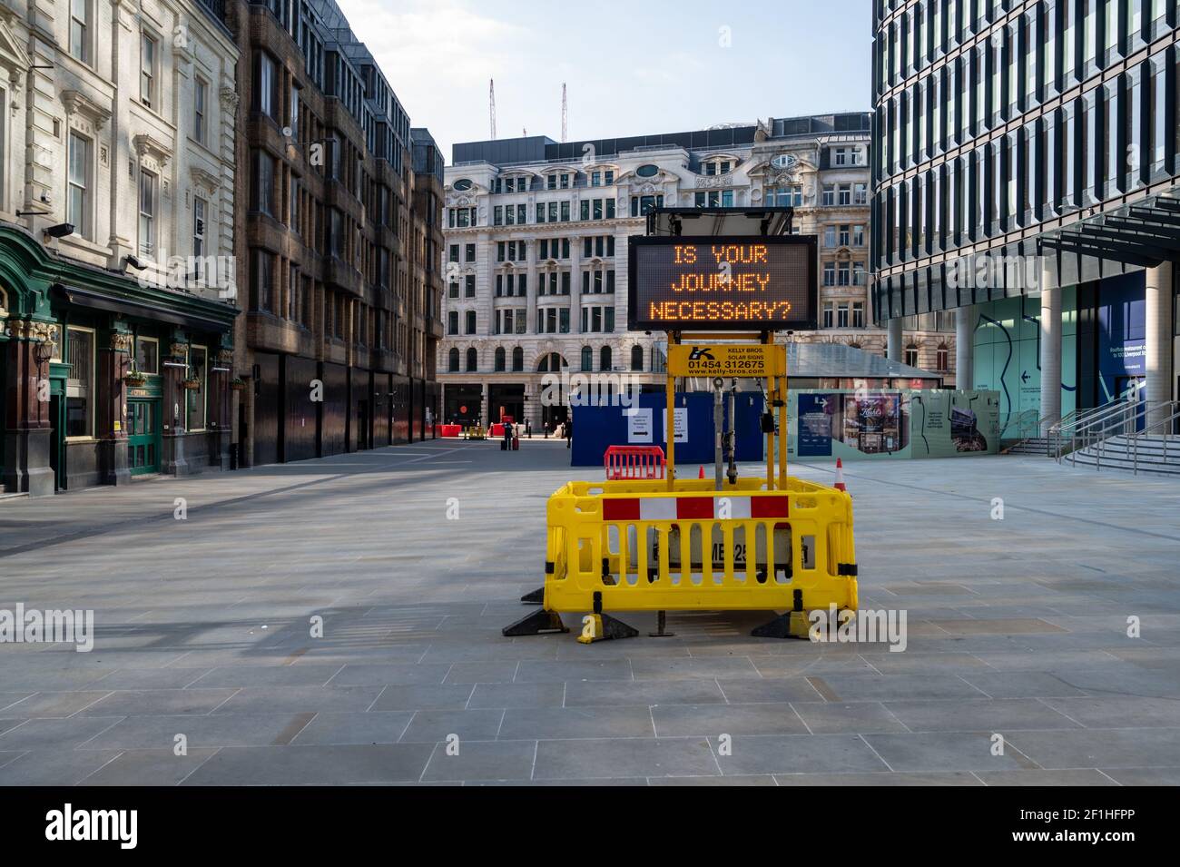 Liverpool Street, London. Covid-Pandemie, dritte Sperre. Ein beleuchtetes Display von "ist Ihre Reise notwendig" gegen eine leere Straße. Stockfoto