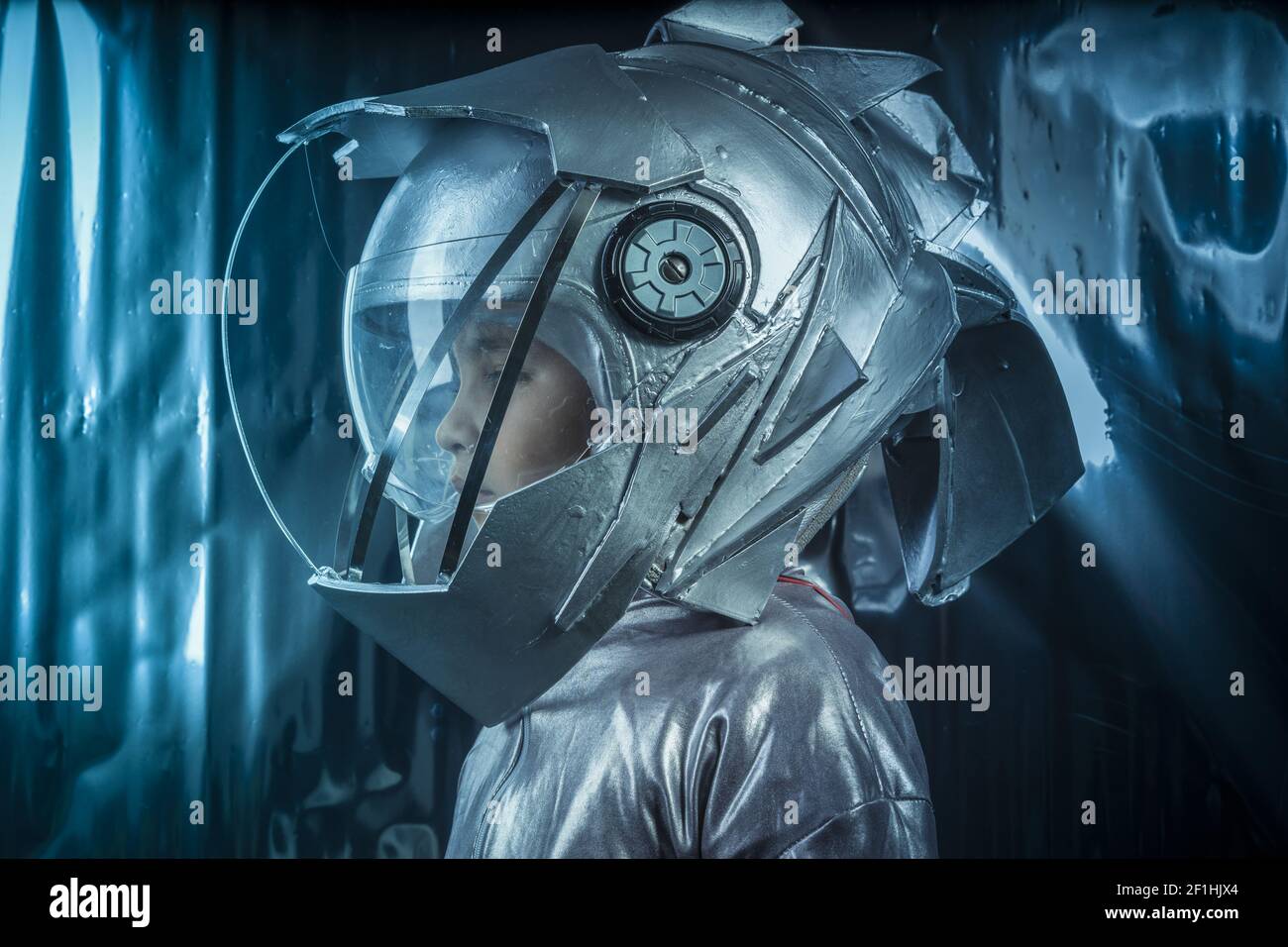 Junge spielt ein Astronaut mit Helm und Silber Anzug auf der metallischen Hintergrund zu sein Stockfoto