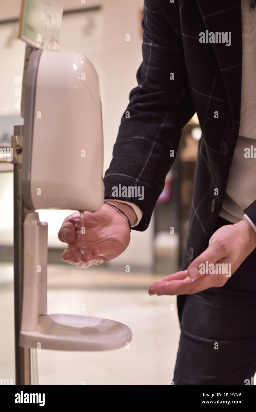 Nahaufnahme der Hand des Mannes mit automatischem Händedesinfektionsgel in einem Einkaufszentrum zur Vorbeugung covid19. Hände waschen. Öffentlicher Raum. Stockfoto