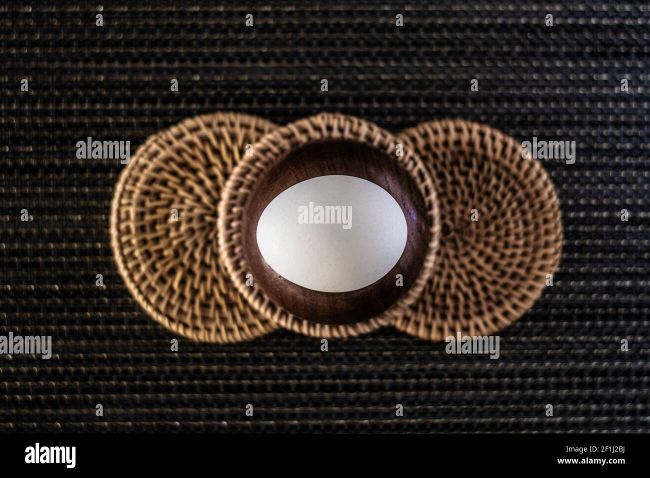 Weißes Hühnerei auf drei gewebten Untersetzern Stockfoto