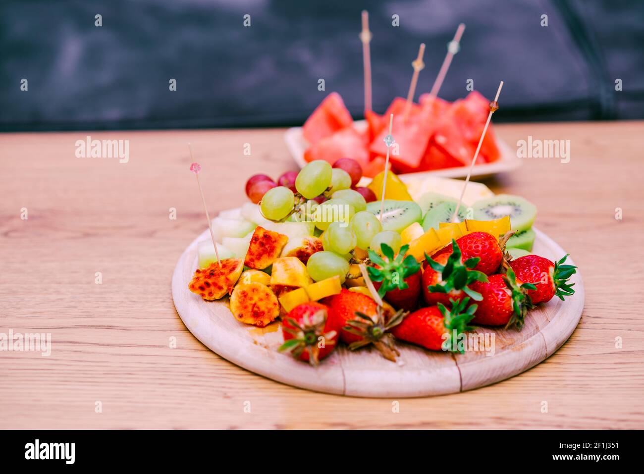 Frisches Obst auf EINEM Holztisch. Rohe Bio-Obstteller Mit Beeren, Melonen, Kiwi, Mango, Ananas, Wassermelone, Kaktuskerne, Karambola, Erdbeere. Stockfoto
