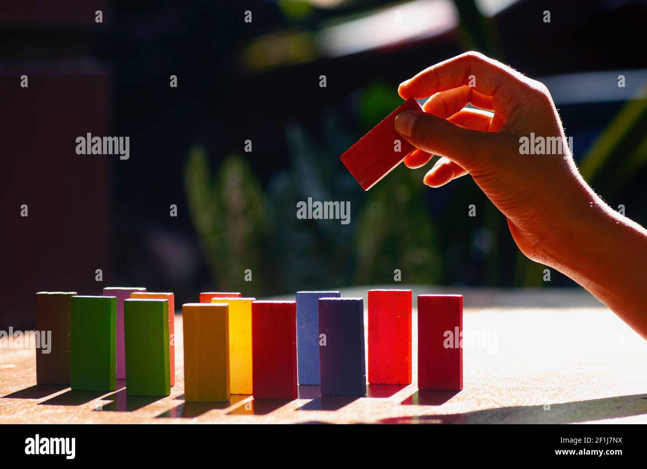 Bunte Holzspielzeug, pädagogische Logik Spielzeug für Kinder mit Kinderhand Nahaufnahme, Hintergrundbeleuchtung Stockfoto