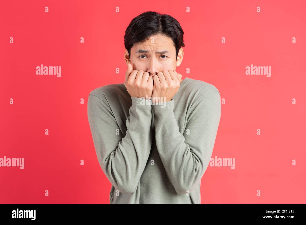 Ein Foto eines hübschen asiatischen Mannes, der sein Gesicht bedeckt Mit seinen Händen in Angst Stockfoto