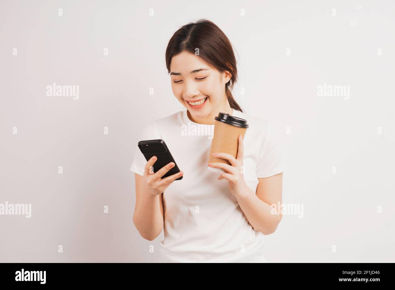 Portrait von jungen asiatischen Mädchen hält Kaffee Tasse und mit Telefon Stockfoto