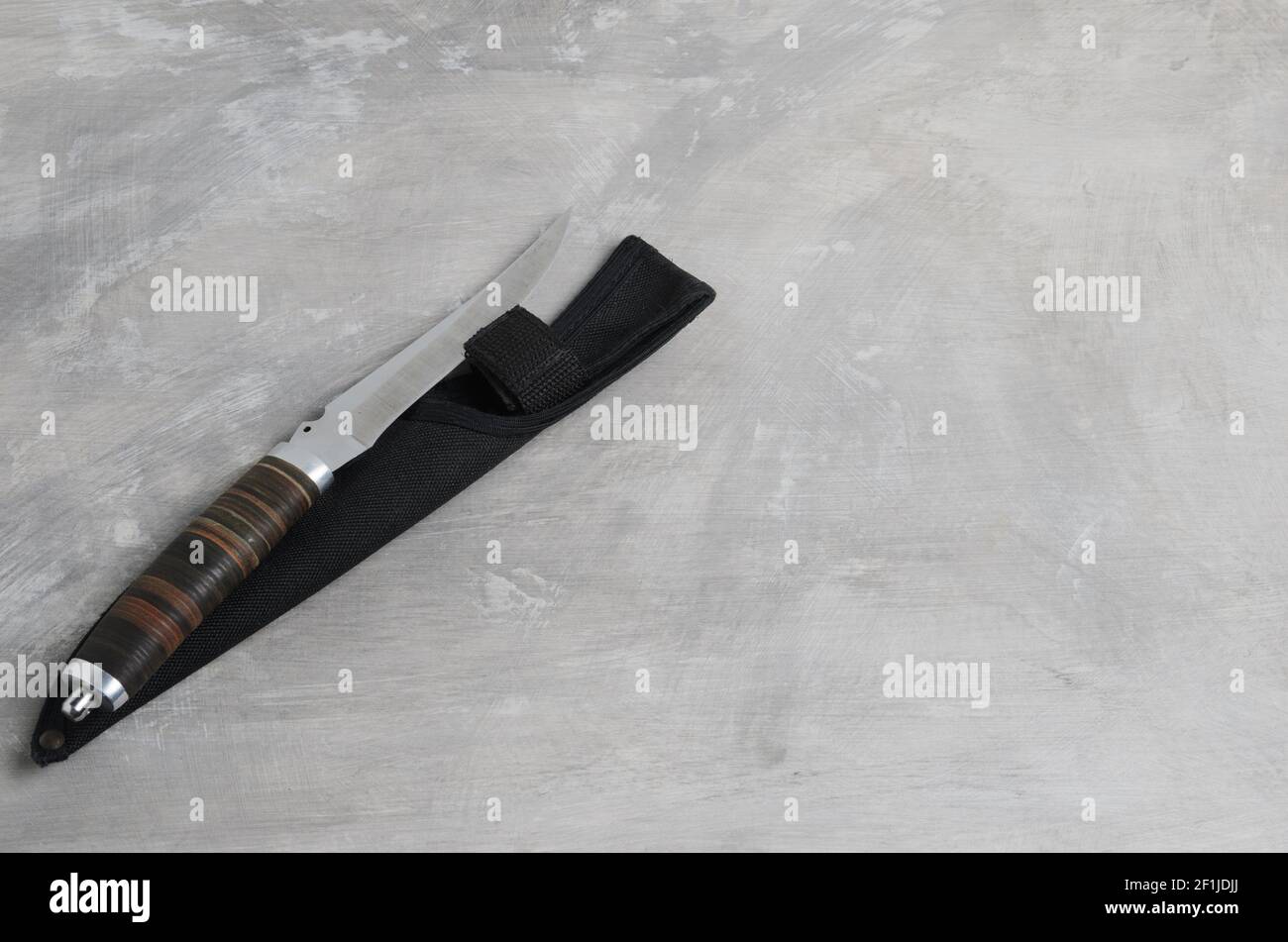 Ein elegantes Jagdmesser mit Scheide und Ledergriff auf einem betongrauen Hintergrund. Selektiver Fokus. Stockfoto