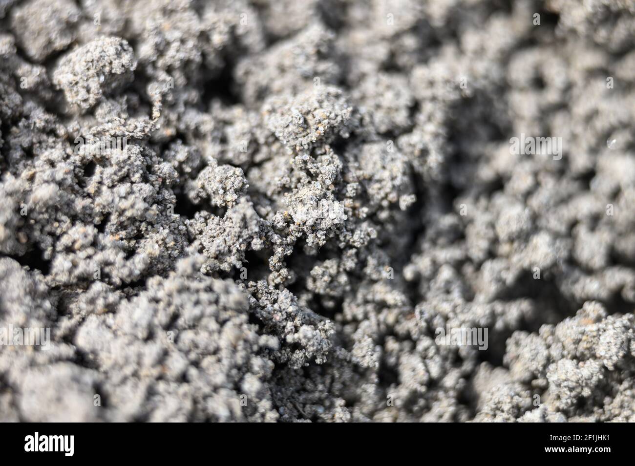 Ein verschwommenes Foto der gezoomten Textur des grauen Bodens der Erde als Hintergrund. Unscharf Stockfoto