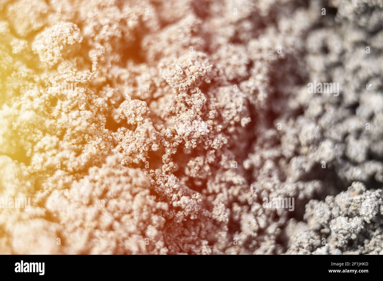 Ein verschwommenes Foto der gezoomten Textur des grauen Bodens der Erde als Hintergrund. Unschärfe. Flare Stockfoto