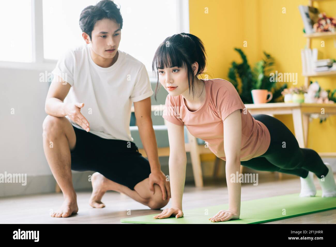 Asian Freund ist instructing seine Freundin zu trainieren zu Hause Stockfoto