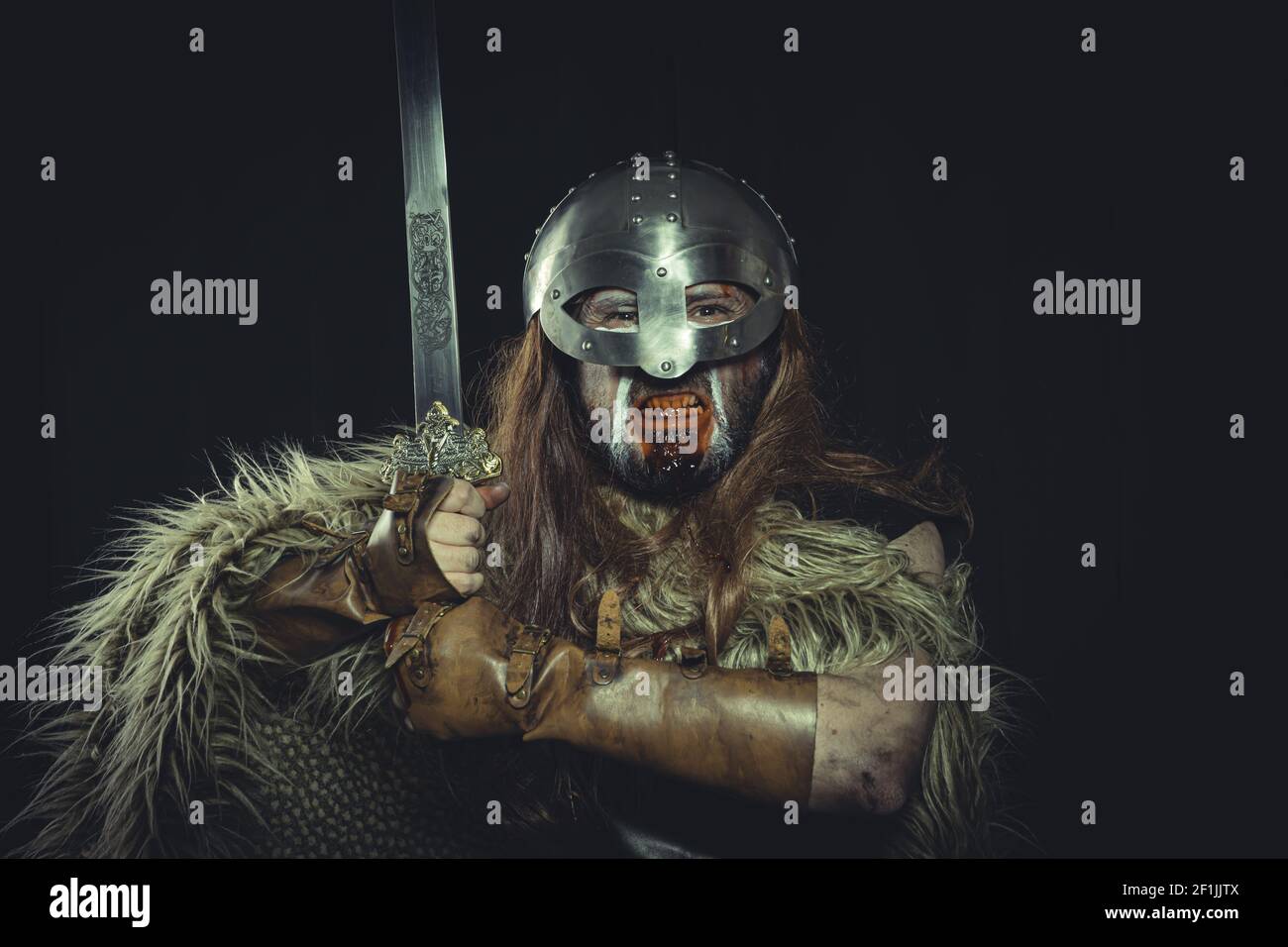 Viking, skandinavischer Krieger mit Helm und Kriegsbildern, trägt ein Schwert und einen Umhang aus Tierhaut Stockfoto
