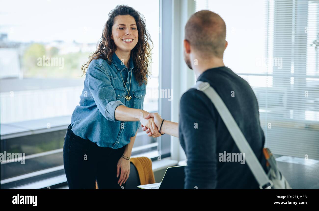 Geschäftsfrau schüttelt einem Bewerber die Hand. Weibliche Profis grüßen die Bewerberin mit einem Handschlag in der Vorstandssitzung. Stockfoto