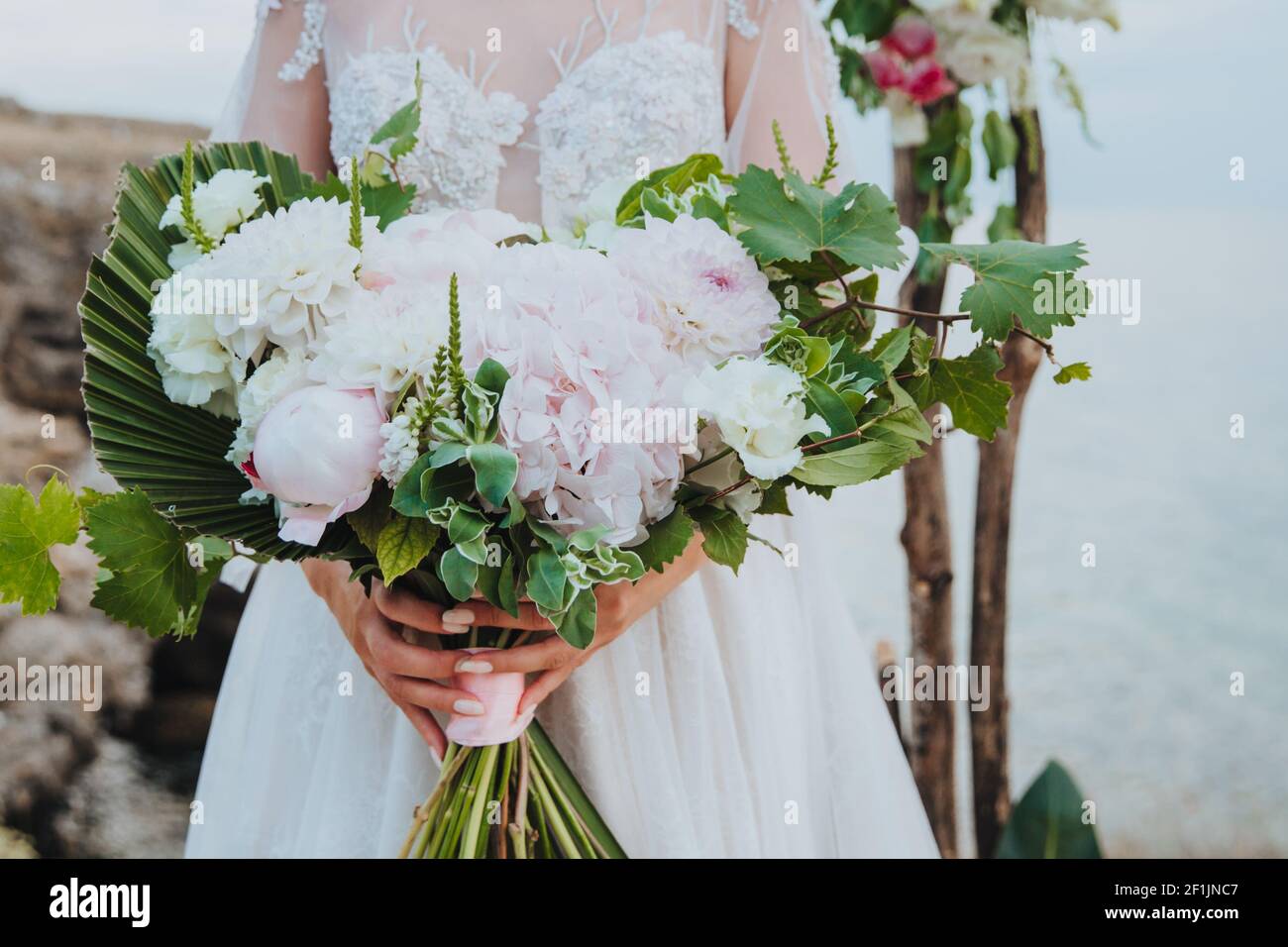 Eine Frau in einem schönen weißen Kleid hält einen wunderschönen Blumenstrauß in ihren Händen. Brautstrauß. Happy Wedding Konzept Stockfoto