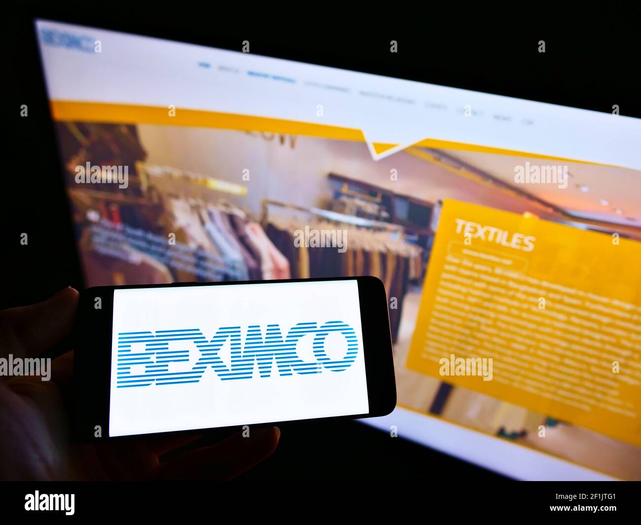 Person, die Handy mit Logo von Bangladesh Export Import Company Limited (BEXIMCO) auf dem Bildschirm vor der Webseite hält. Konzentrieren Sie sich auf die Telefonanzeige. Stockfoto