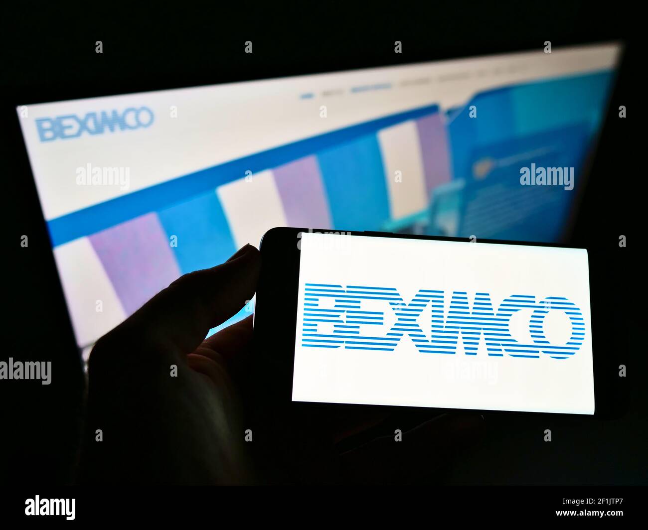 Person, die Handy mit Logo von Bangladesh Export Import Company Limited (BEXIMCO) auf dem Bildschirm vor der Webseite hält. Konzentrieren Sie sich auf die Telefonanzeige. Stockfoto