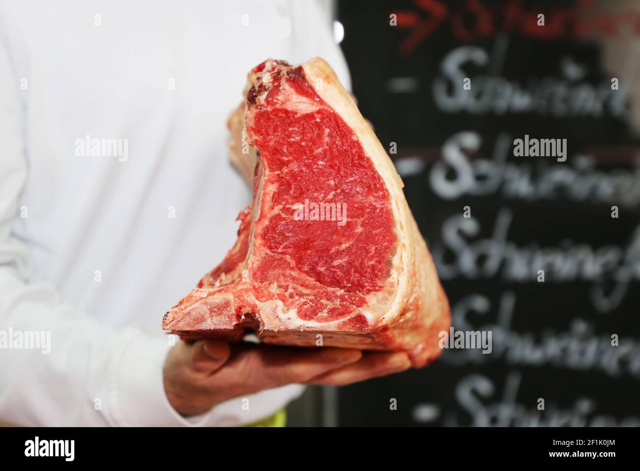 Metzger hält trocken gereiftes T-Bone Steak in der Hand Stockfoto