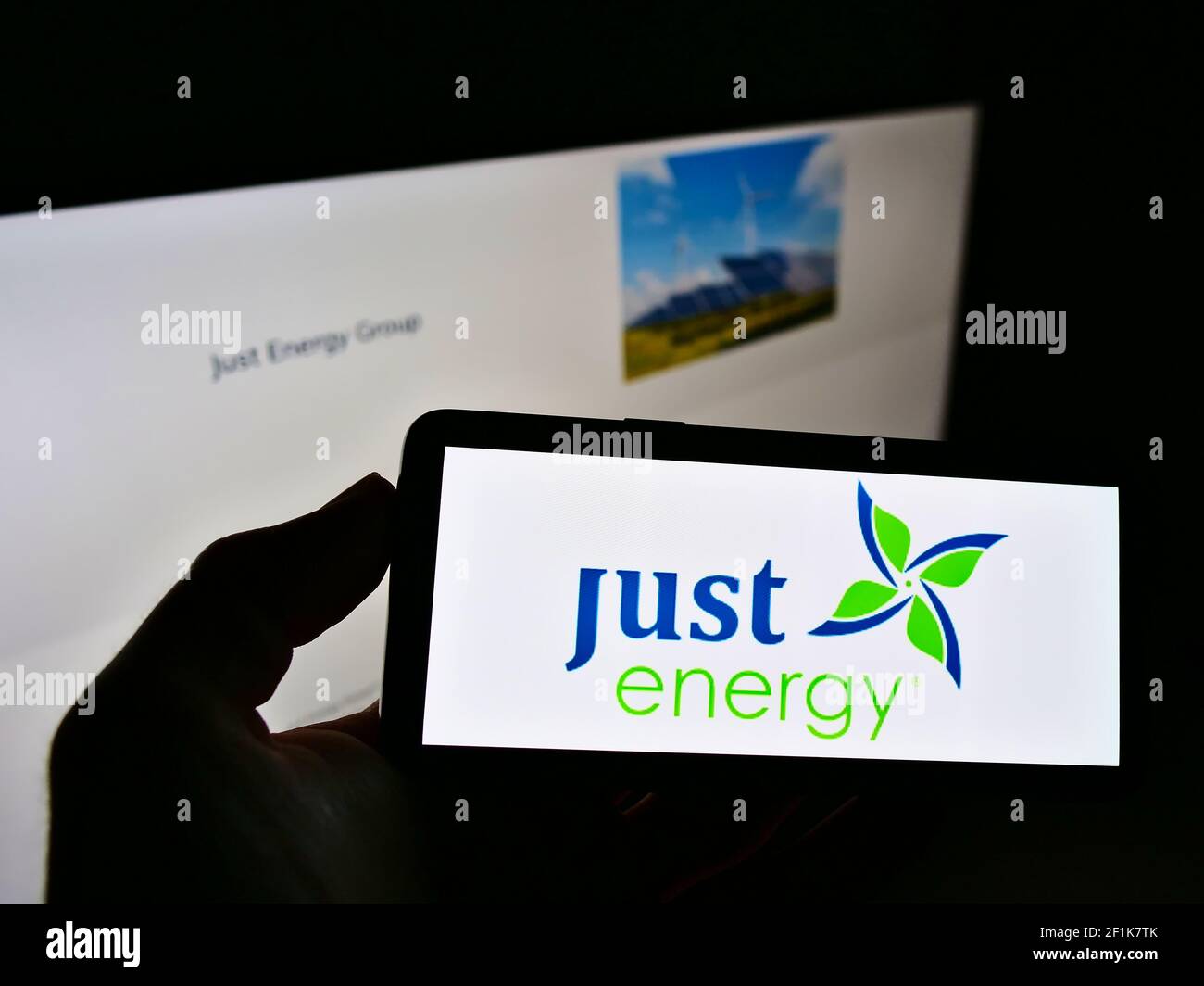 Person mit Mobiltelefon und Logo des kanadischen Elektrizitätsunternehmens Just Energy Group Inc. Auf dem Bildschirm vor der Webseite. Konzentrieren Sie sich auf die Telefonanzeige. Stockfoto