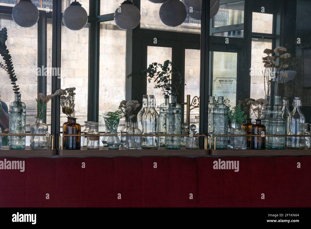 Dekorative Glasflaschen säumen die Wand in einem gemütlichen kleinen Restaurant in Rennes mit verspiegelten Wänden und Stockfoto