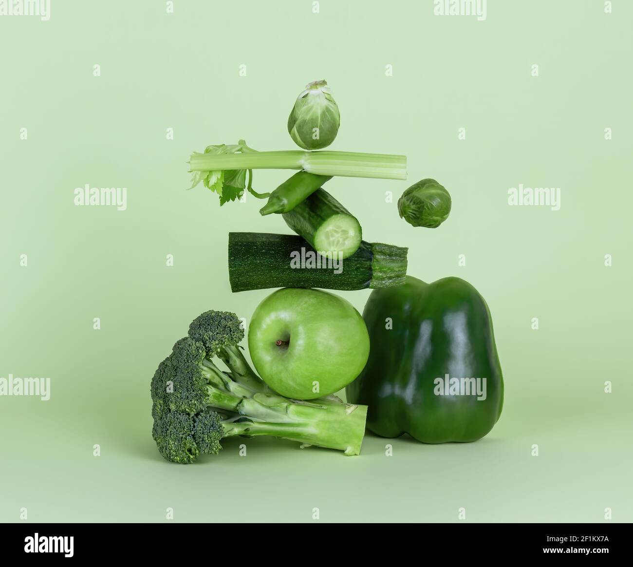 Frisches grünes Gemüse und Obst auf grünem Hintergrund. Gleichgewicht schwimmende Lebensmittelbalance. Stockfoto