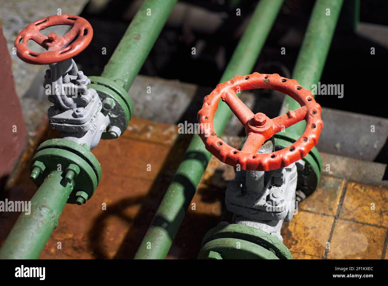 Zwei industrielle chemische petrochemische Retro-Stil grüne Ventile Closeup mit Selektive Fokussierung auf rotes Lenkrad mit Flanschanschluss Ein Stockfoto