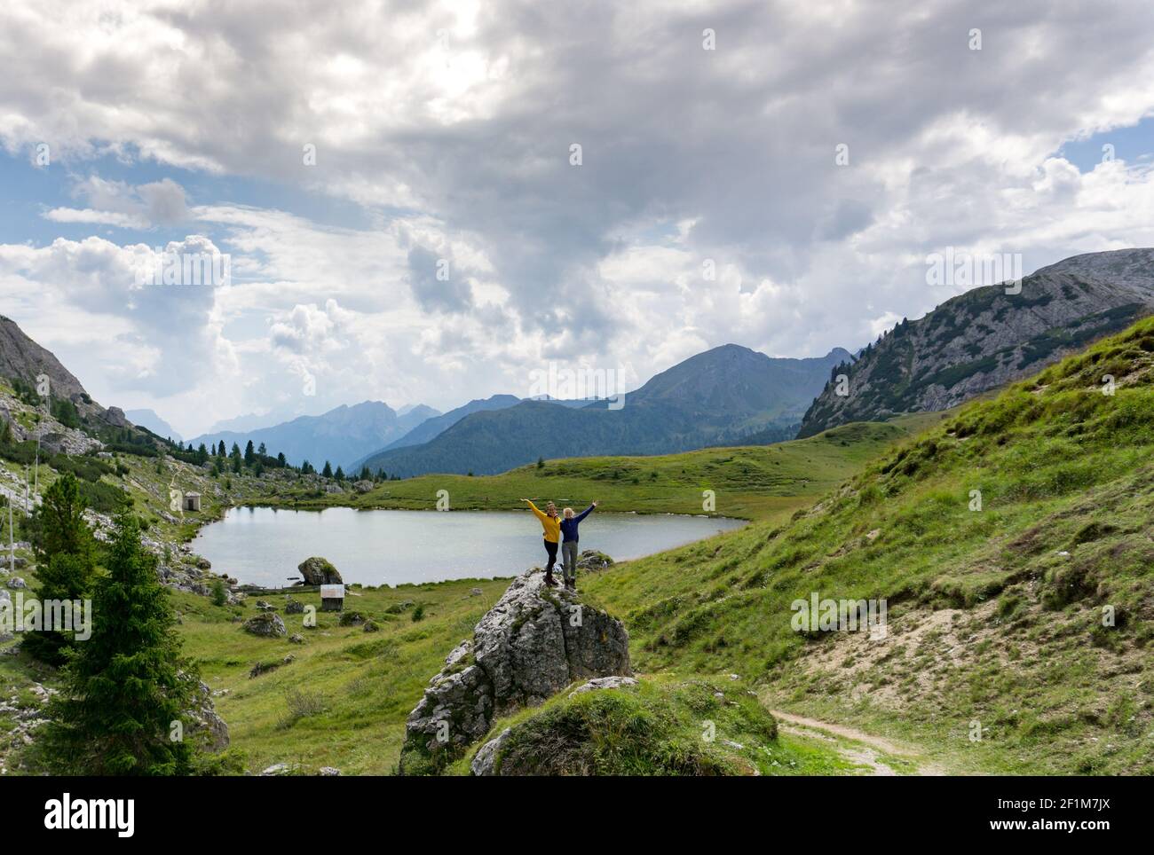 Zwei Wanderinnen stehen auf einem Felsbrocken in einem hübschen Berglandschaft in den Dolomiten und Welle Stockfoto