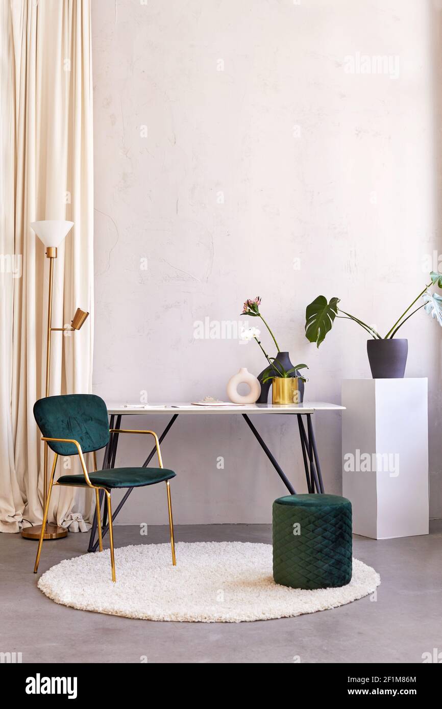 Tisch mit Blumen in geräumigen Zimmer mit Stühlen platziert Stilvolle Wohnung mit minimalistischem Interieur Stockfoto