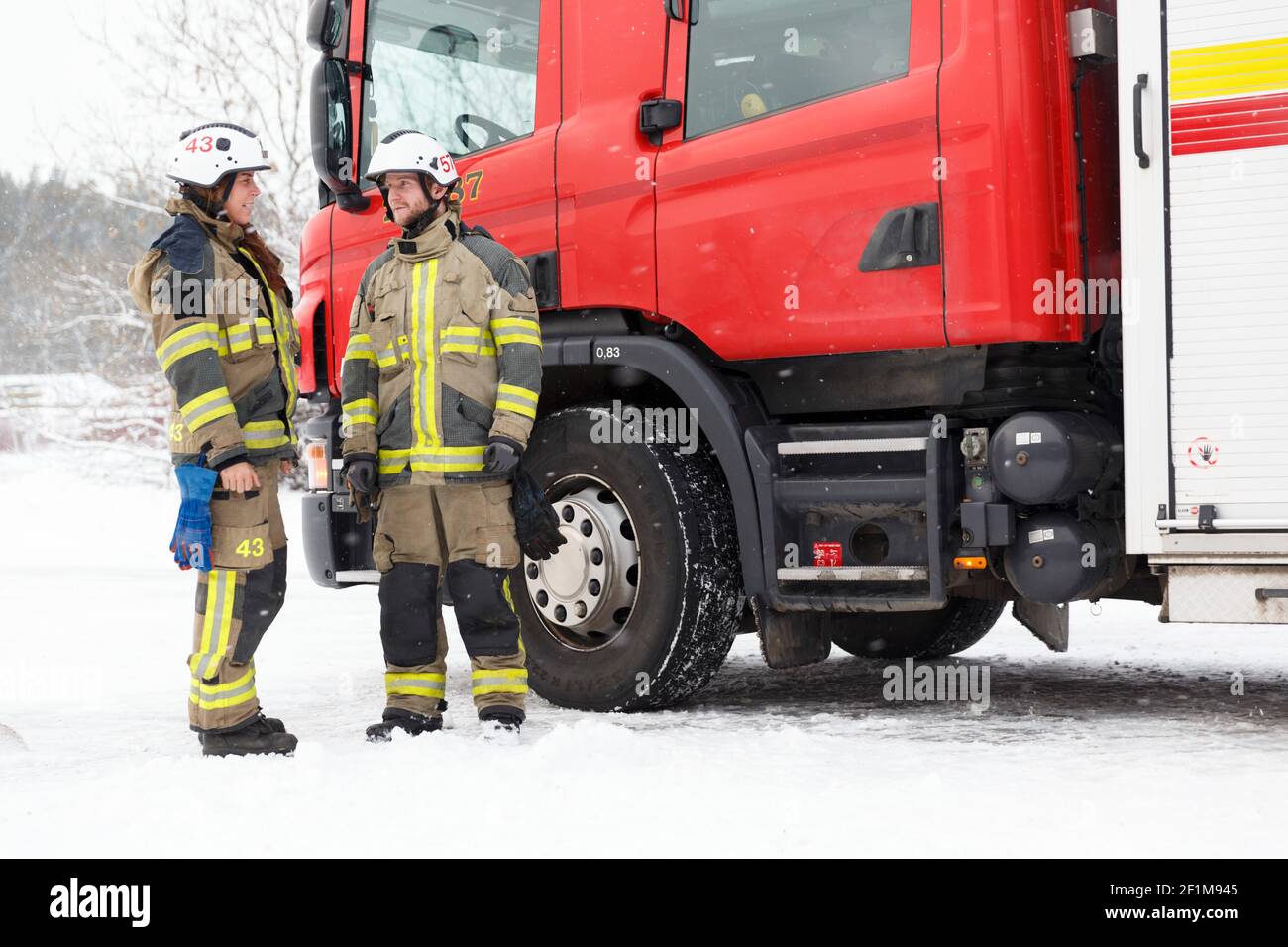 Feuerwehrleute sprechen vor dem Feuerwehrmotor Stockfoto